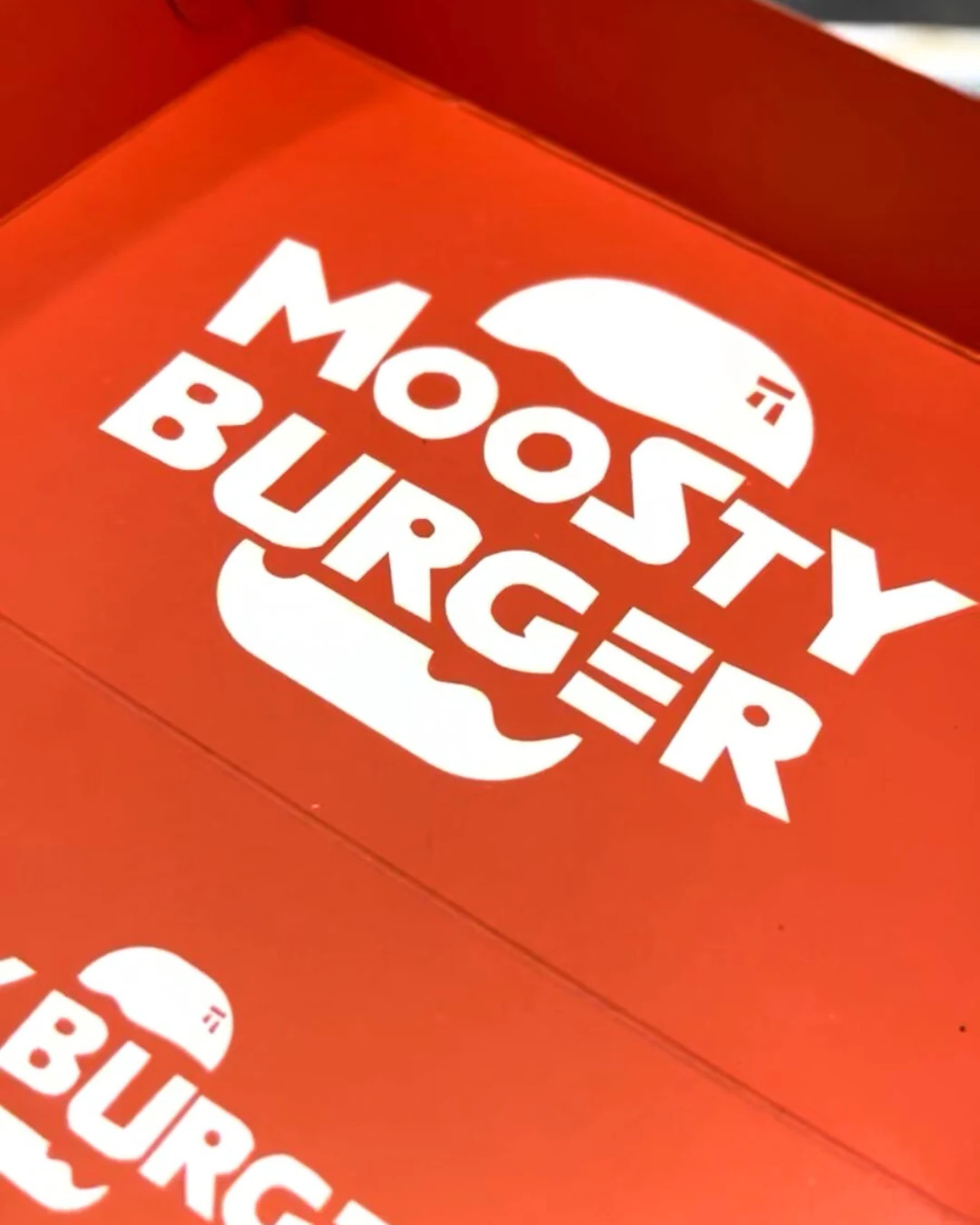 moosty-burguer-destacada-caja-hamburguesa-empaques-kreat-up-2 Bandeja de cartón kraft roja personalizada para alimentos, diseñada por KreatUp, con logo y gráficos de hamburguesa Moosty.