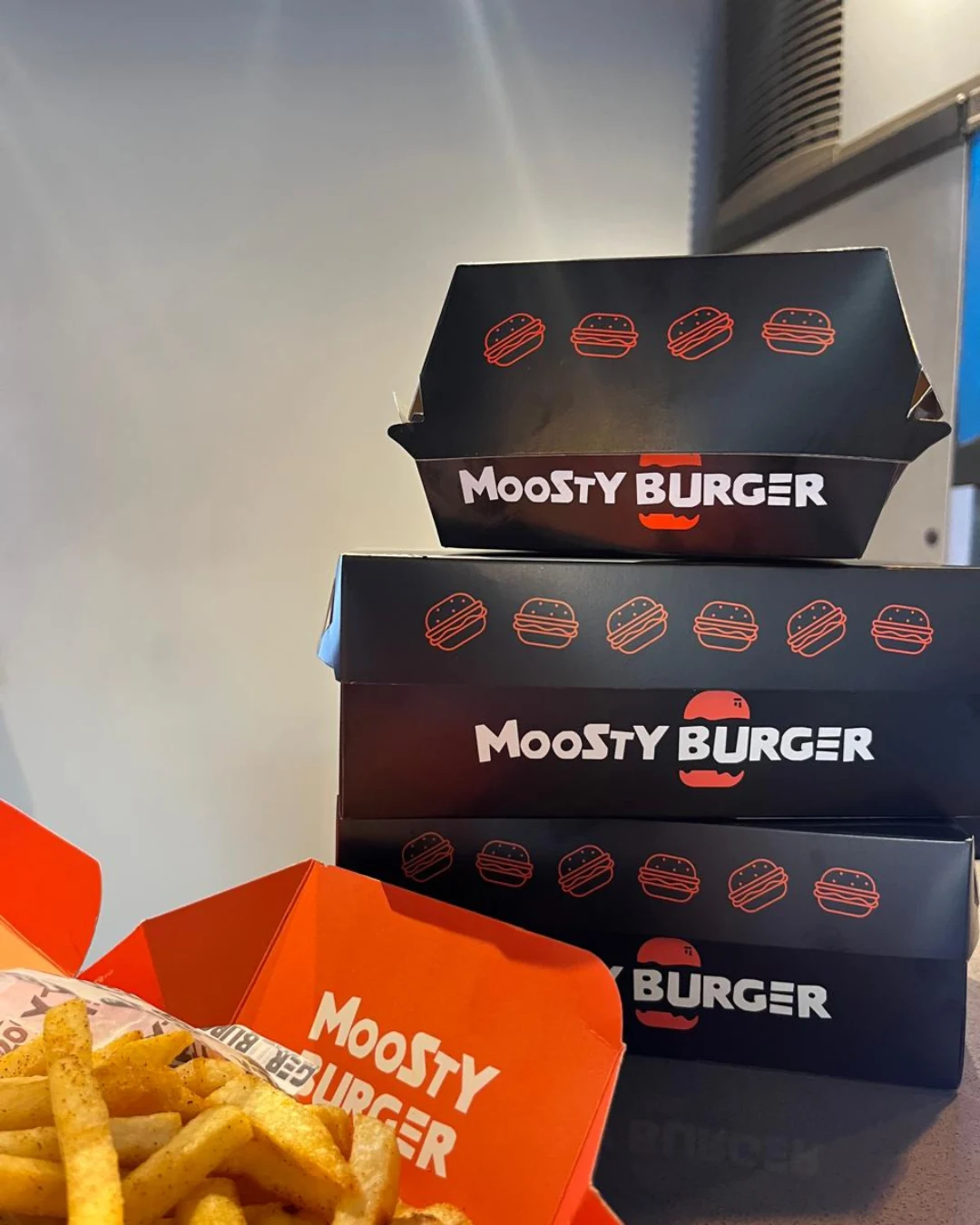 Moosty Burger 1 Cajas personalizadas de cartón kraft negro y naranja para alimentos, diseñadas por KreatUp para Moosty Burger.