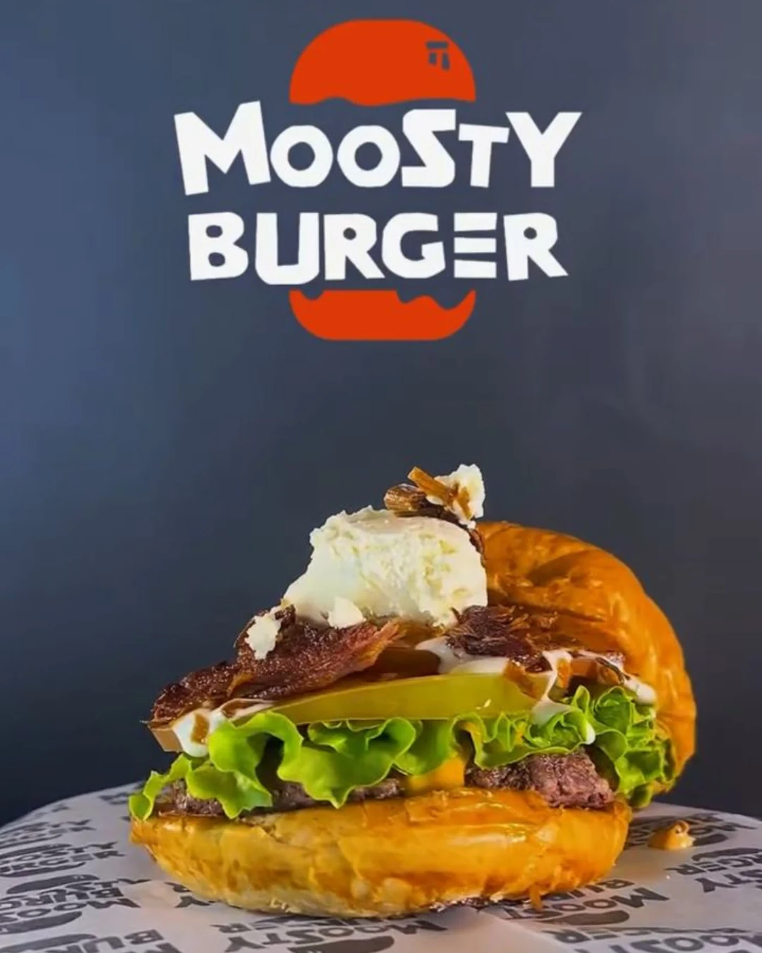 moosty-burguer-destacada-papel-parafinado-empaques-kreat-up Caja para hamburguesa Moosty Burger de cartón kraft personalizada con logotipo rojo y blanco, diseñada por KreatUp.